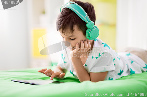 Image of smiling boy with tablet pc and headphones at home