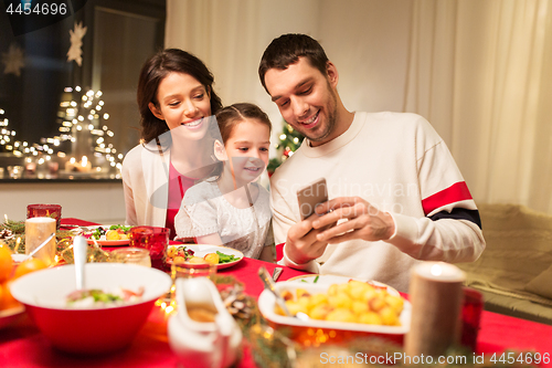 Image of family with smartphone having christmas dinner