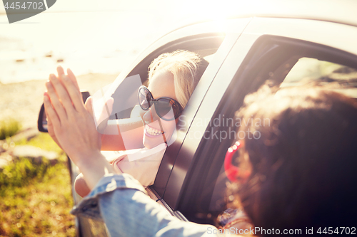 Image of happy teenage girls or women in car at seaside