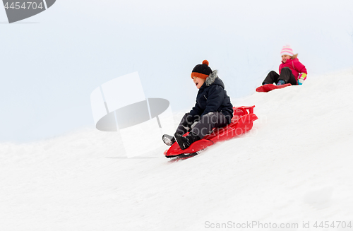 Image of happy kids sliding on sleds down hill in winter