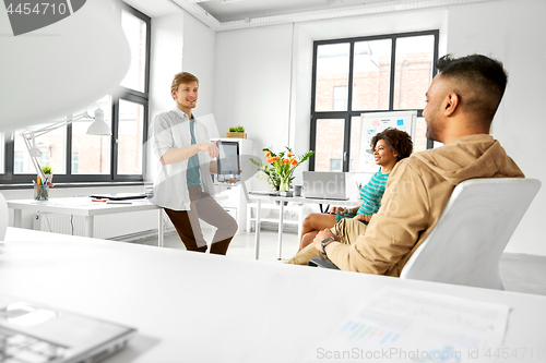 Image of man showing tablet pc to creative team at office