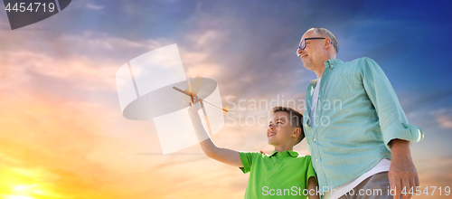 Image of senior man and boy with toy airplane over sky