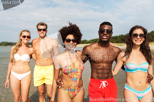 Image of happy friends hugging on summer beach