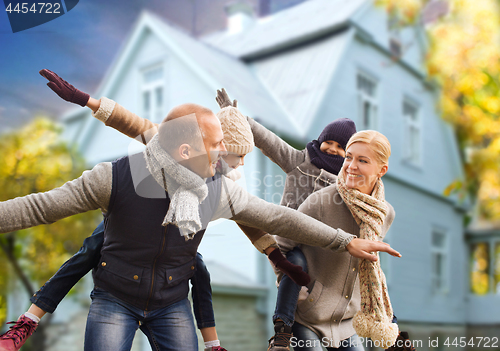 Image of happy family having fun over house in autumn