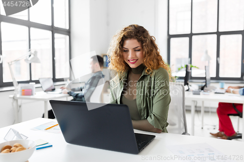 Image of creative woman with laptop working at office