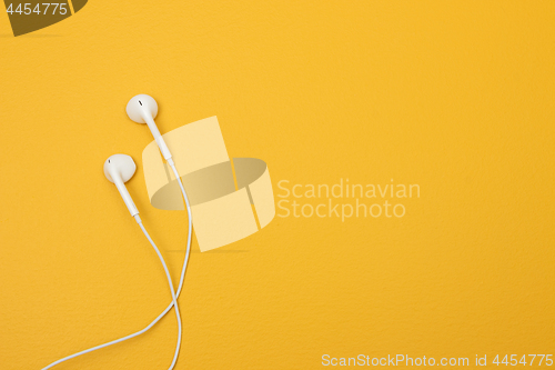 Image of White earphones on yellow background with space for text