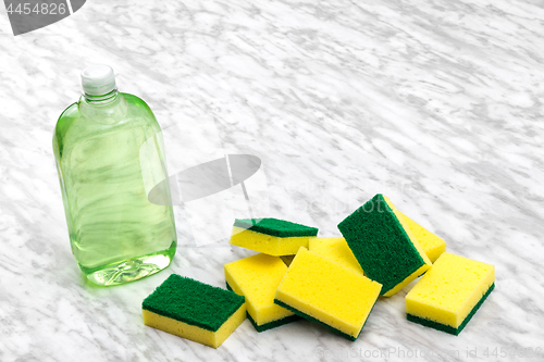 Image of Dishwashing liquid and sponges on marble kitchen countertop