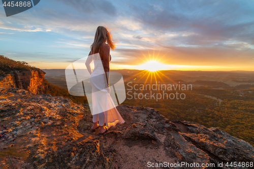 Image of Woman watching blissful sunsets from hidden cliff ledges