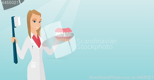 Image of Dentist with a dental jaw model and a toothbrush.