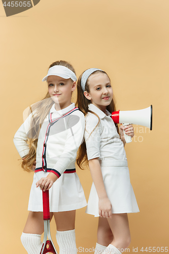 Image of Portrait of two girls as tennis players holding tennis racket. Studio shot.