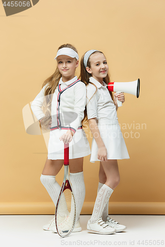 Image of Portrait of two girls as tennis players holding tennis racket. Studio shot.