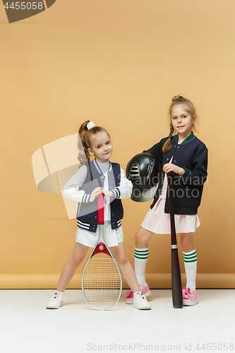 Image of Portrait of two girls as tennis players holding tennis racket. Studio shot.