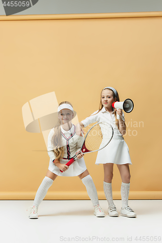 Image of Portrait of two girls as tennis players holding tennis racket. Studio shot.