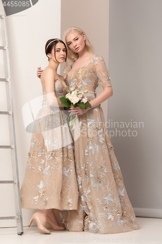 Image of Brides in beautiful dress standing indoors in white studio interior like at home. Trendy wedding style shot. Young attractive caucasian model like a bride tender looking.