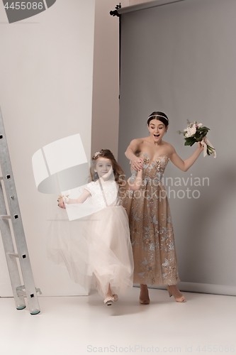 Image of Little pretty girls with flowers dressed in wedding dresses