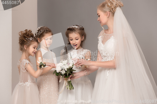 Image of Little pretty girls with flowers dressed in wedding dresses