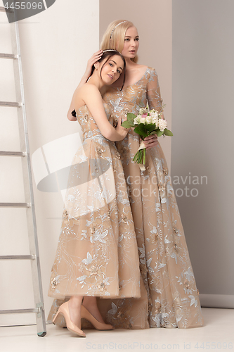 Image of Brides in beautiful dress standing indoors in white studio interior like at home. Trendy wedding style shot. Young attractive caucasian model like a bride tender looking.