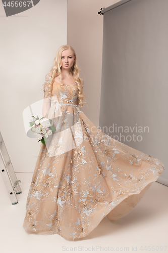 Image of Bride in beautiful dress standing indoors in white studio interior like at home. Trendy wedding style shot. Young attractive caucasian model like a bride tender looking.
