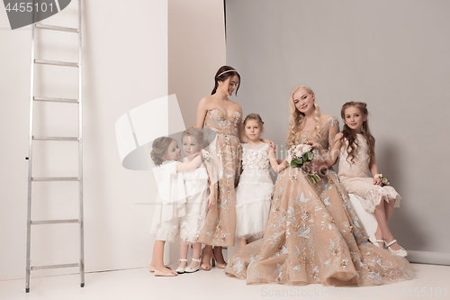 Image of Little pretty girls with flowers dressed in wedding dresses