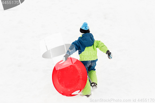 Image of happy boy with snow saucer sled in winter