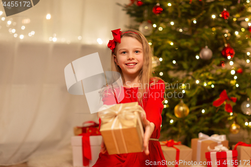 Image of smiling girl with christmas gift at home