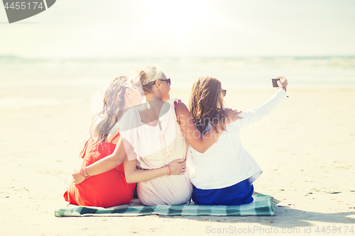 Image of happy women taking selfie by smartphone on beach