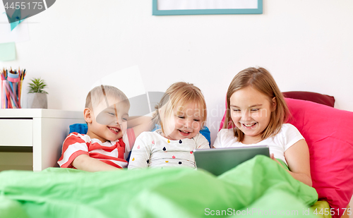 Image of little kids with tablet pc in bed at home