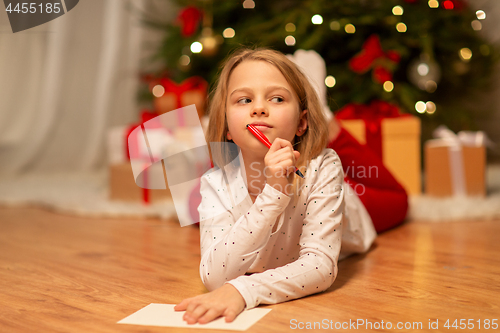 Image of girl writing christmas wish list at home