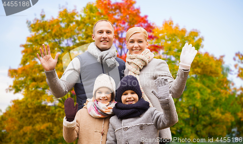 Image of happy family waving hands over autumn park