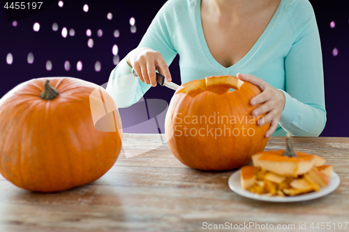 Image of close up of woman carving halloween pumpkin