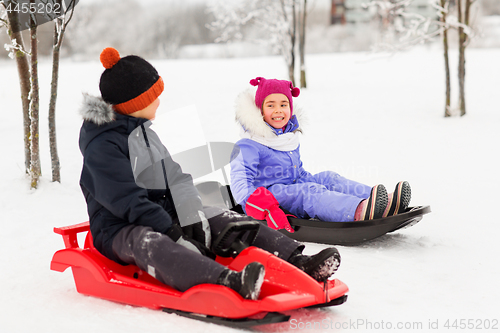 Image of happy little kids sliding on sleds in winter