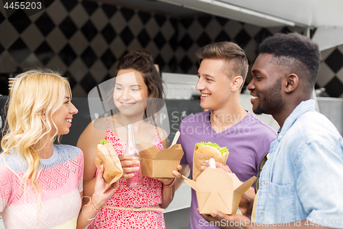 Image of happy friends with drinks eating at food truck