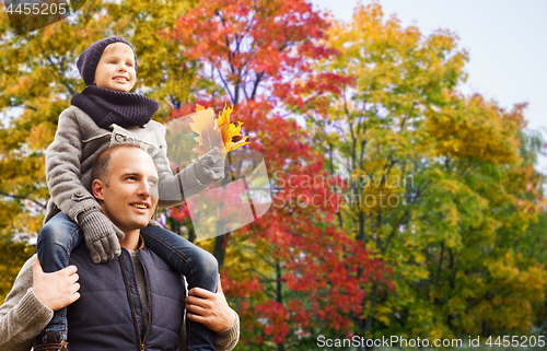 Image of happy father carrying son with autumn maple leaves