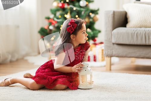 Image of little girl with lantern at home on christmas