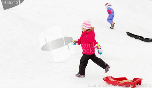 Image of little girl with sleds on snow hill in winter