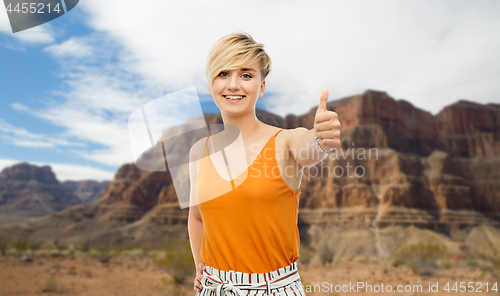 Image of happy smiling young woman showing thumbs up