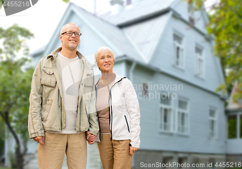 Image of happy senior couple holding hands over house