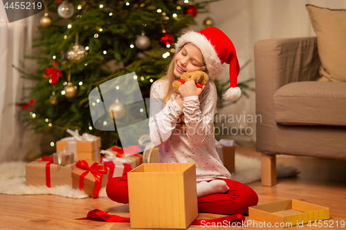 Image of smiling girl in santa hat with christmas gift