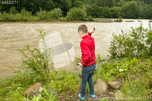 Image of Little boy throwing stones in the water