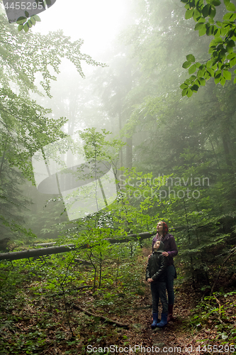 Image of Mother and son in the mystic green foggy forest. The are looking
