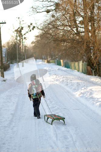 Image of Little boy is carrying sleigh