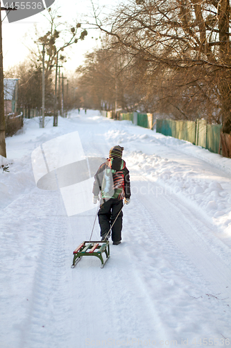 Image of Little boy is carrying sleigh