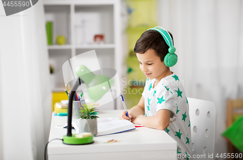 Image of boy in headphones with textbook learning at home