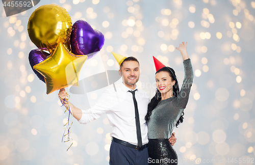 Image of happy couple in party hats with balloons