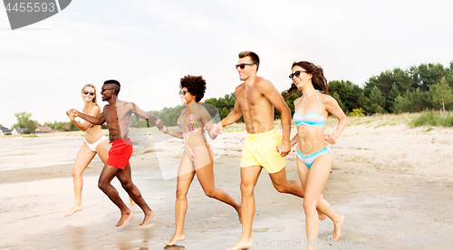 Image of happy friends running on summer beach