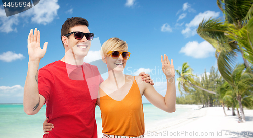 Image of couple in sunglasses hugging and waving hands