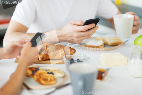 Image of close up of couple with smartphones at breakfast