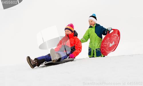 Image of kids sliding on sleds down snow hill in winter