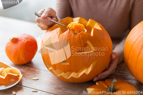 Image of close up of woman carving halloween pumpkin