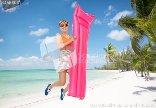 Image of teenage girl jumping with float mattress on beach